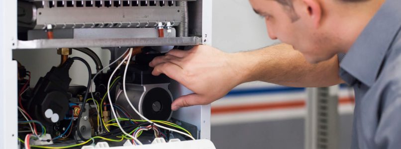 A person is repairing an open printer or copier machine, examining the internal components consisting of wires and mechanical parts. Focus is on maintenance work.