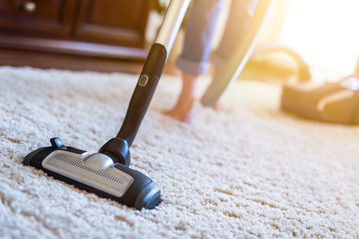 Vacuuming cleaner while cleaning carpet in the house.