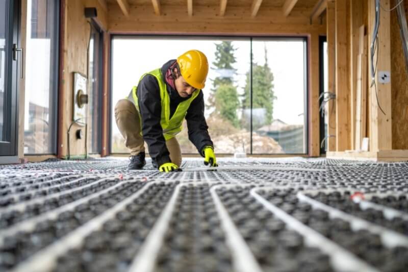 A photo of a worker installing in-floor heating for a new custom home.