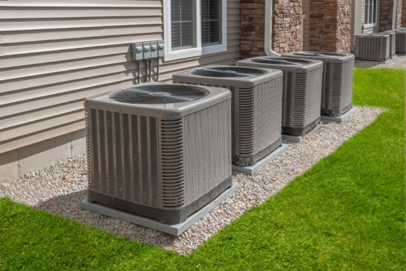 A photo of four heat pumps lined up outside of a new home.