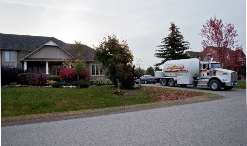 A photo of a Bryan's Fuel propane delivery truck in the driveway of a home in fall.