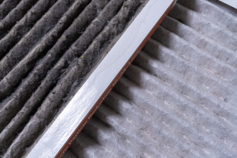 A close-up photo of a dirty furnace filter beside a new furnace filter.