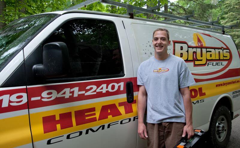 A photo of a Bryan's Fuel Service Tech standing beside a Bryan's Fuel service vehicle in the summer.