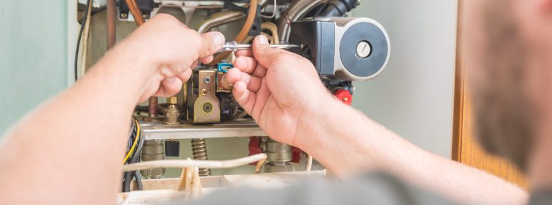 A photo of a man repairing a gas furnace.