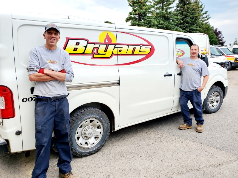 A photo of two Bryan's Fuel service employees standing beside a Bryan's Fuel service van.