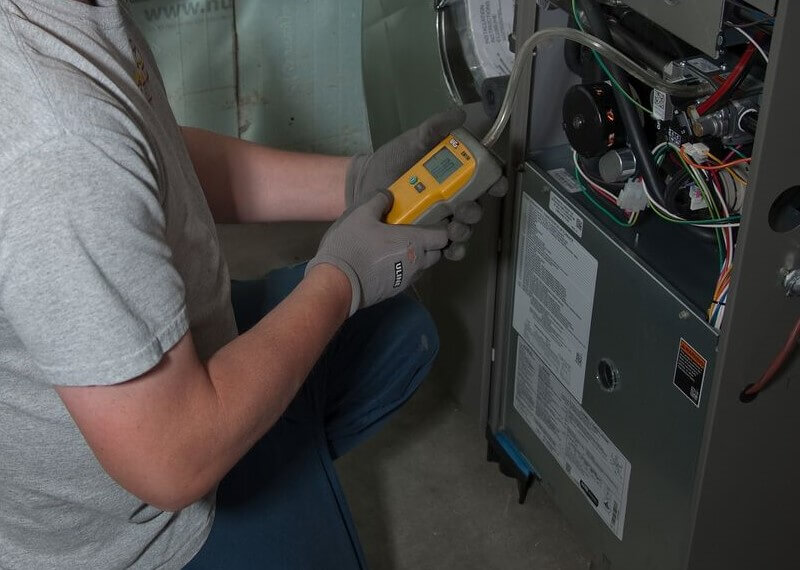 A photo of a Bryan's Fuel HVAC service tech working on a furnace. 