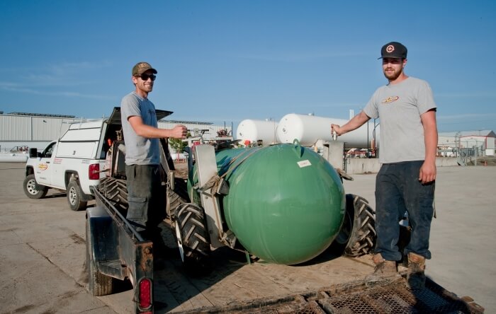 A photo of two Bryan's Fuel employees, standing in the back of a truck next to a green propane tank.