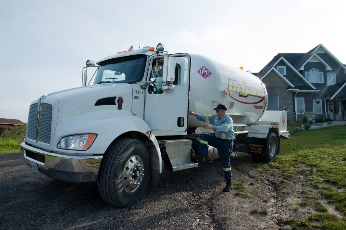 A Bryan's Fuel employee getting into a propane delivery truck, in the driveway of a rural home.