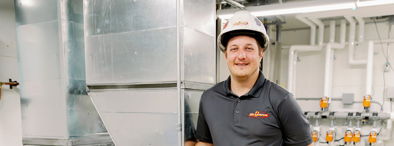 Bryan's Fuel team member standing next to a new HVAC unit.