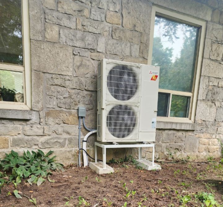 A photo of a newly-installed heat pump next to a home.