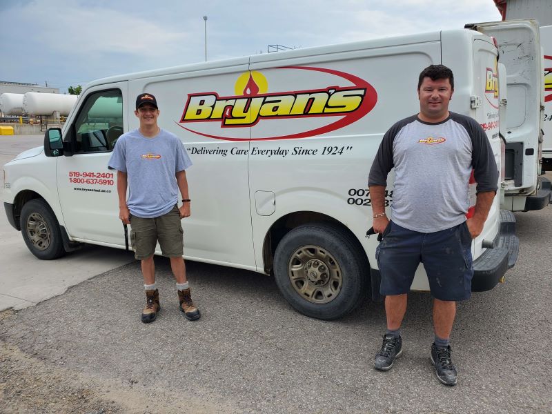 A photo of two Bryan's Fuel HVAC Technicians standing in front of a branded van.