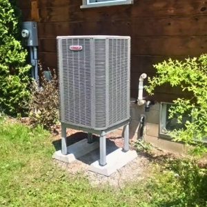 A photo of a Lennox Heat Pump beside a house in the summer.