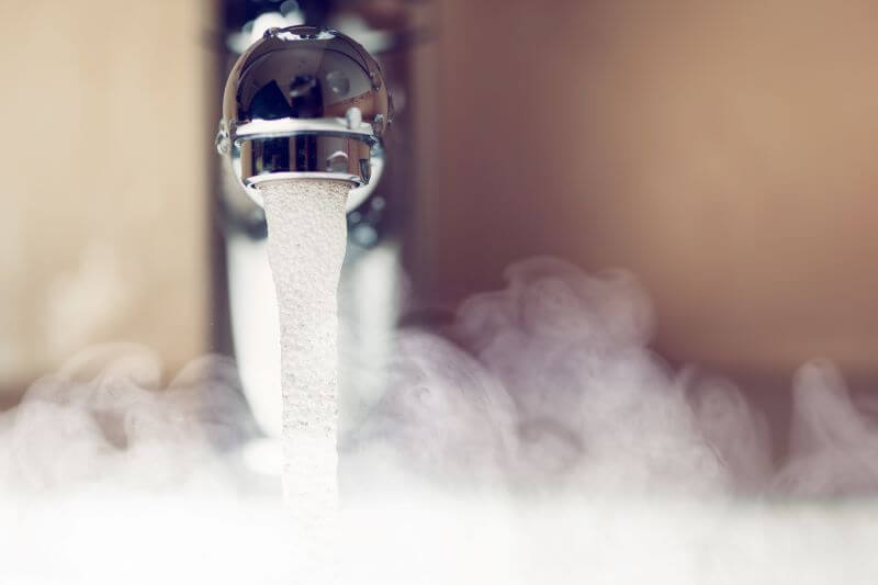 A photo of hot water pouring out of a kitchen faucet. 
