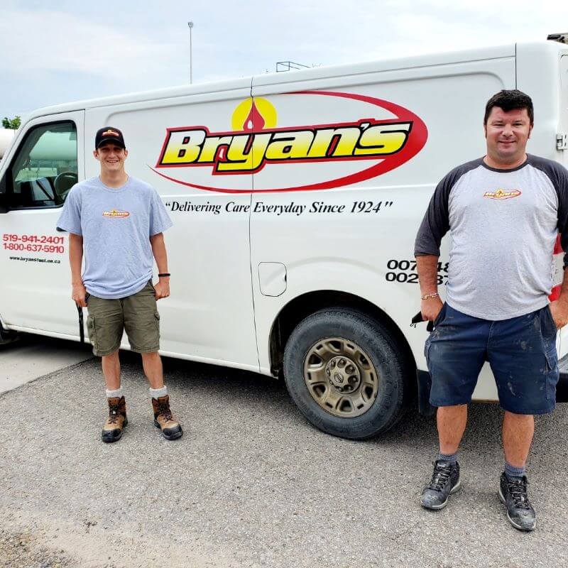 A photo of two Bryan's Fuel team members standing in front of a service van.