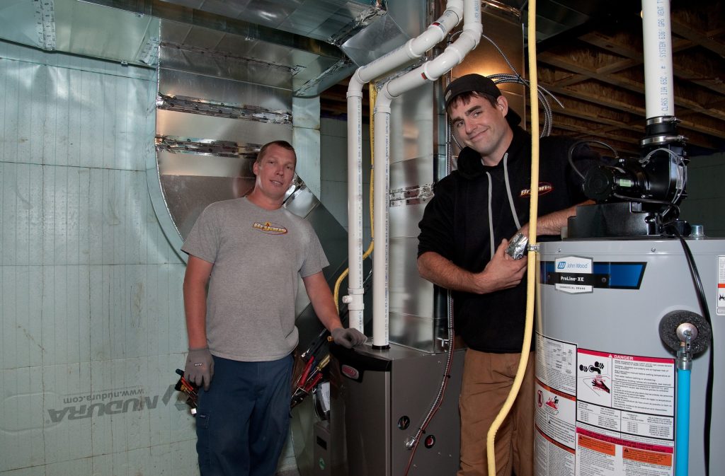 Bryan's Fuel technicians beside an HVAC system.