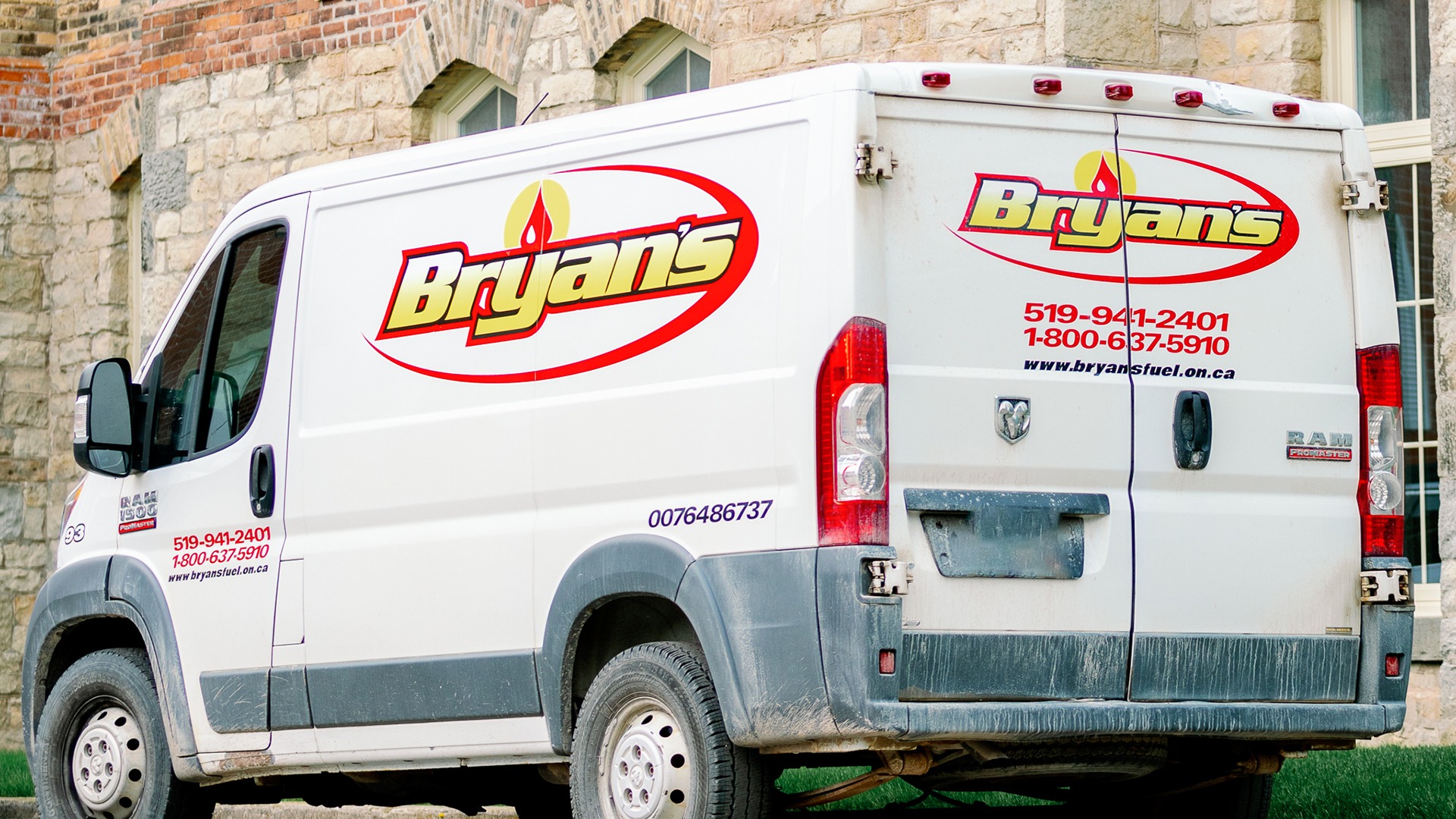 White van with "Bryan's" logo parked beside stone building. Contact numbers and website visible on vehicle. Grass partially visible beneath.