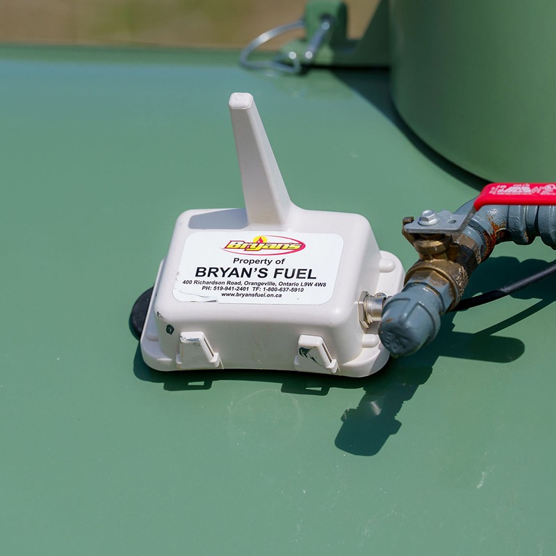 A fuel monitoring device labeled "Bryan's Fuel" is attached to a green tank, with a connected valve and hose visible alongside.