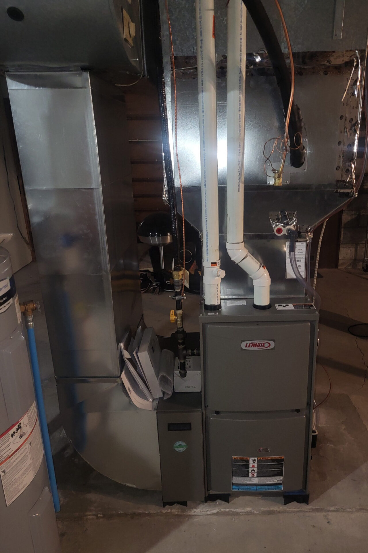 Basement with a Lennox furnace setup, water heater, and visible piping. The area is well-organized, showcasing essential home heating elements.