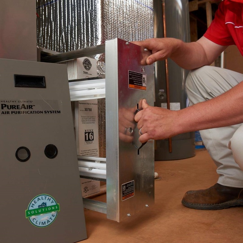 A photo of a Bryan's Fuel employee servicing a Lennox Air Purifier installed in a house.