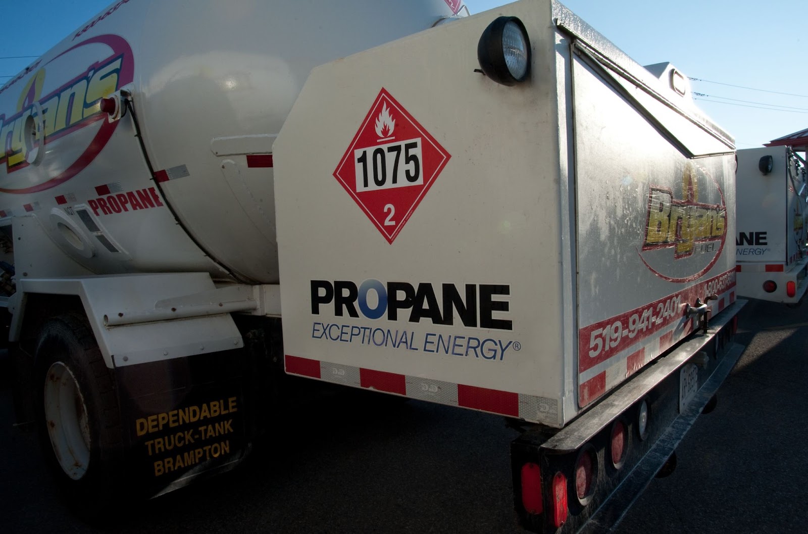A propane delivery truck with safety label "1075" and "EXCEPTIONAL ENERGY" branding is parked, displaying company contact information on the side.