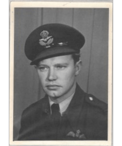 A person in a military uniform, wearing a cap with an emblem, is photographed in grayscale against a plain background.