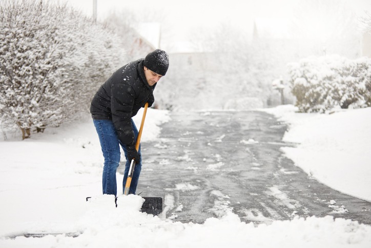 A man shoveling a long driveway.