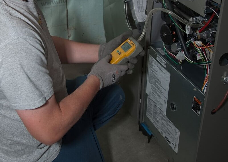 A photo of a Bryan's Fuel HVAC service tech working on a furnace.