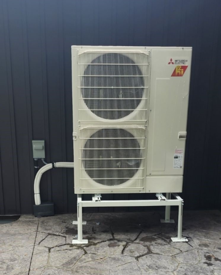 A photo of a newly-installed heat pump next to a home.