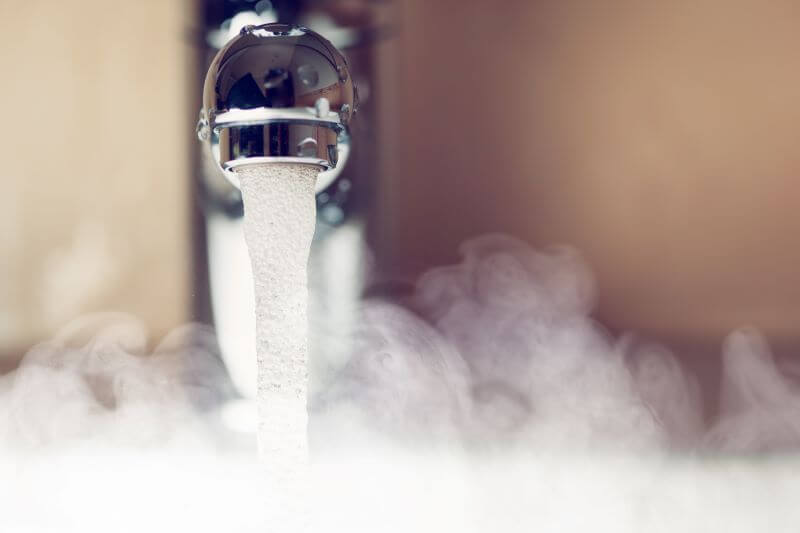 A photo of hot water pouring out of a kitchen faucet.